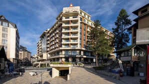 A multi-story hotel with a prominent sign, a central courtyard, and a staircase leading to the entrance.