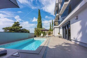 A swimming pool with lounge chairs, a pergola, and tall trees. - Fantastic vacation apartment in Crikvenica, with swimming pool (Crikvenica)
