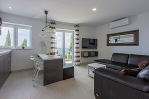 A modern living room with a sofa, a dining area with chairs, a TV, and a large window with curtains. - Fantastic vacation apartment in Crikvenica, with swimming pool (Crikvenica)