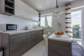 A modern kitchen with a microwave, sink, and fruit bowl on the counter. - Fantastic vacation apartment in Crikvenica, with swimming pool (Crikvenica)