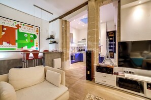 A modern living room with a sofa, a TV, and a kitchen in the background. - LUXURY LOFT IN THE CENTER OF PARIS (Paris)