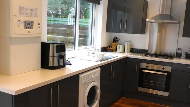 Een moderne keuken met een ingebouwde wasmachine, een fornuis en een groot raam.