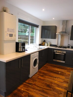 A modern kitchen with a built-in washer, a stove, and a large window.