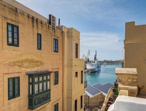 Un bâtiment situé sur la côte, offrant une vue sur un port, avec un grand navire amarré au quai.