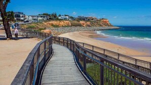 A wooden boardwalk leading to a beach with houses in the background.