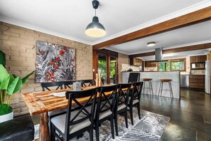 Une cuisine moderne dotée d’un îlot central, de poutres en bois et d’une grande fenêtre.
