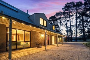 A building with a brick facade, large windows, and a covered outdoor area with string lights.