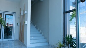 A modern interior with a staircase, glass doors, and potted plants. - Silicon Heights Studio Apartment Gold (Accra)