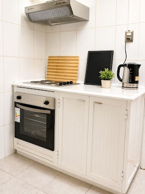 A kitchen with a stove, oven, microwave, and a kettle on the counter.