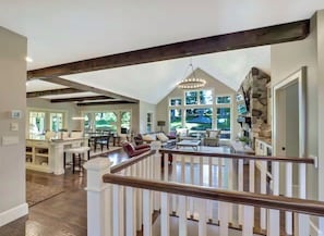 Een ruime woonkamer met een hoge plafond, een accentmuur van steen en uitzicht op het buitengebied.