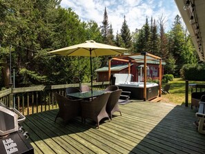 A wooden deck with outdoor furniture, a hot tub, and a covered area with a grill. - Le Kaïa, Bord de L`eau, Plage, spa et foyer (Nominingue)
