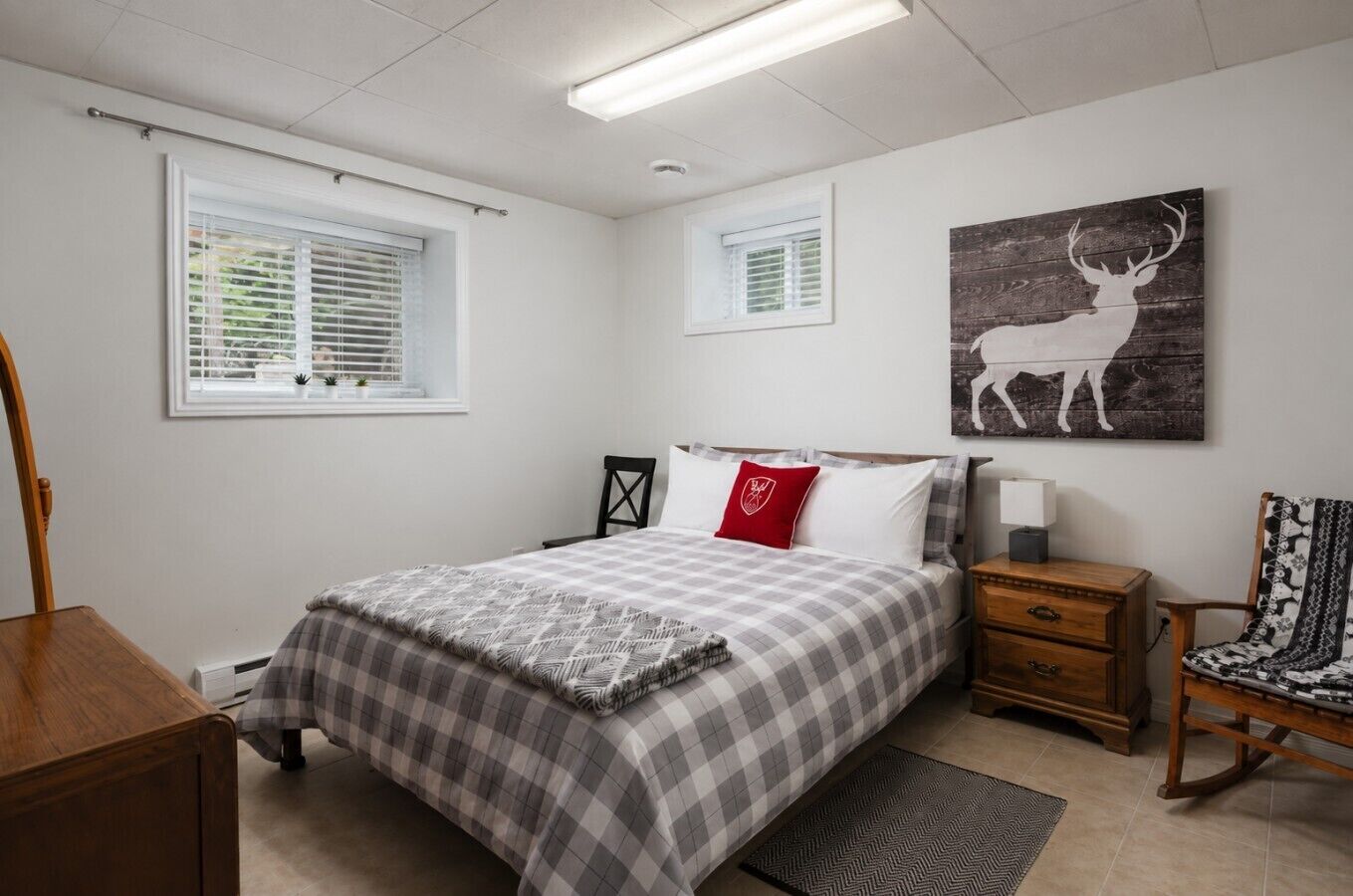 A bedroom with a bed, bedside tables, a chair, a window, and a wall-mounted artwork.