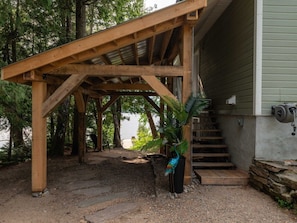 Eine Holzhütte mit einer Pergola und einer Treppe, die zu einem Gebäude führt.