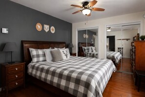 A bedroom with a large bed, a nightstand, a dresser, and a ceiling fan. - La Baie la Vida,Bord de L`eau,Spa et foyer (Nominingue)