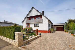 A two-story house with a red and white exterior, a balcony, and a paved driveway. - Apartment 'Gabis' with Shared Terrace, Shared Garden and Wi-Fi (Munningen)