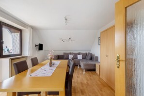 A modern living room with a wooden dining table, a sofa, and a wooden door. - Apartment 'Gabis' with Shared Terrace, Shared Garden and Wi-Fi (Munningen)