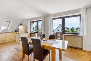A modern kitchen with a dining area, large windows, and a view of the neighborhood.