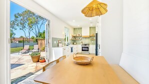 Una cucina moderna con mobili bianchi, un'area pranzo con un tavolo in legno e un cesto di vimini sul tavolo.