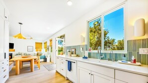 Una cucina moderna con zona pranzo, ampie finestre e ventilatore a soffitto.
