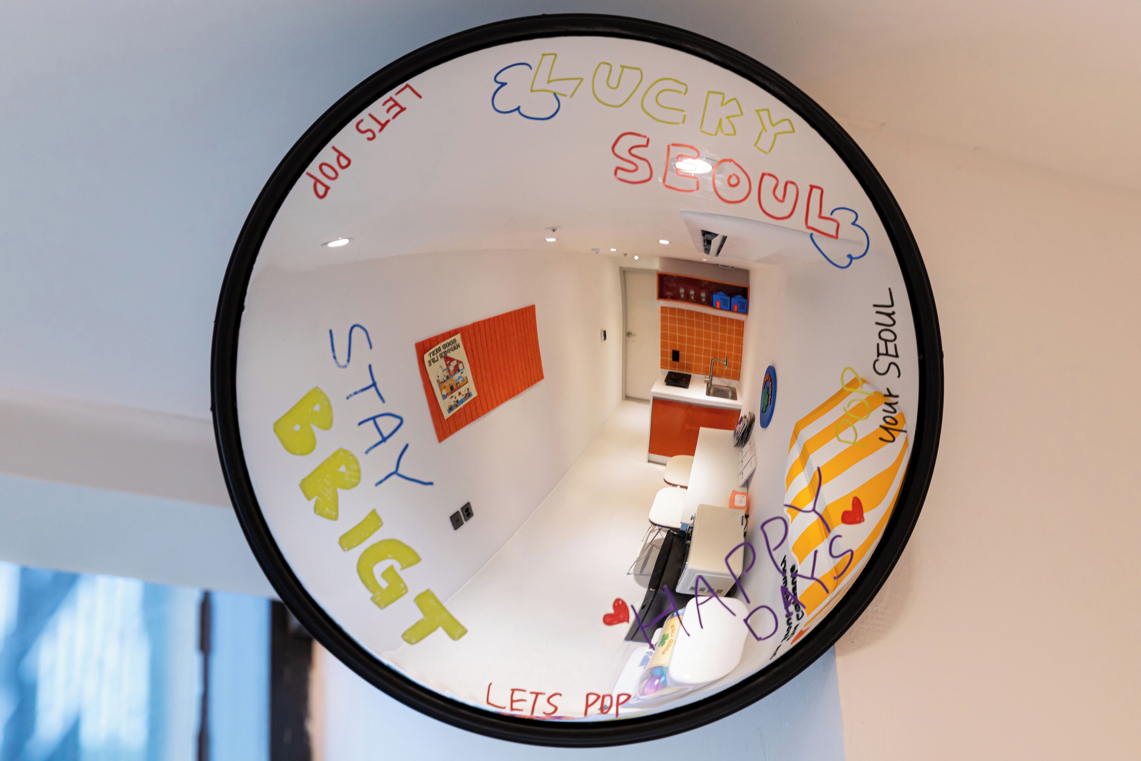Espejo circular con frases motivacionales y vista de una habitación con escritorio y silla.