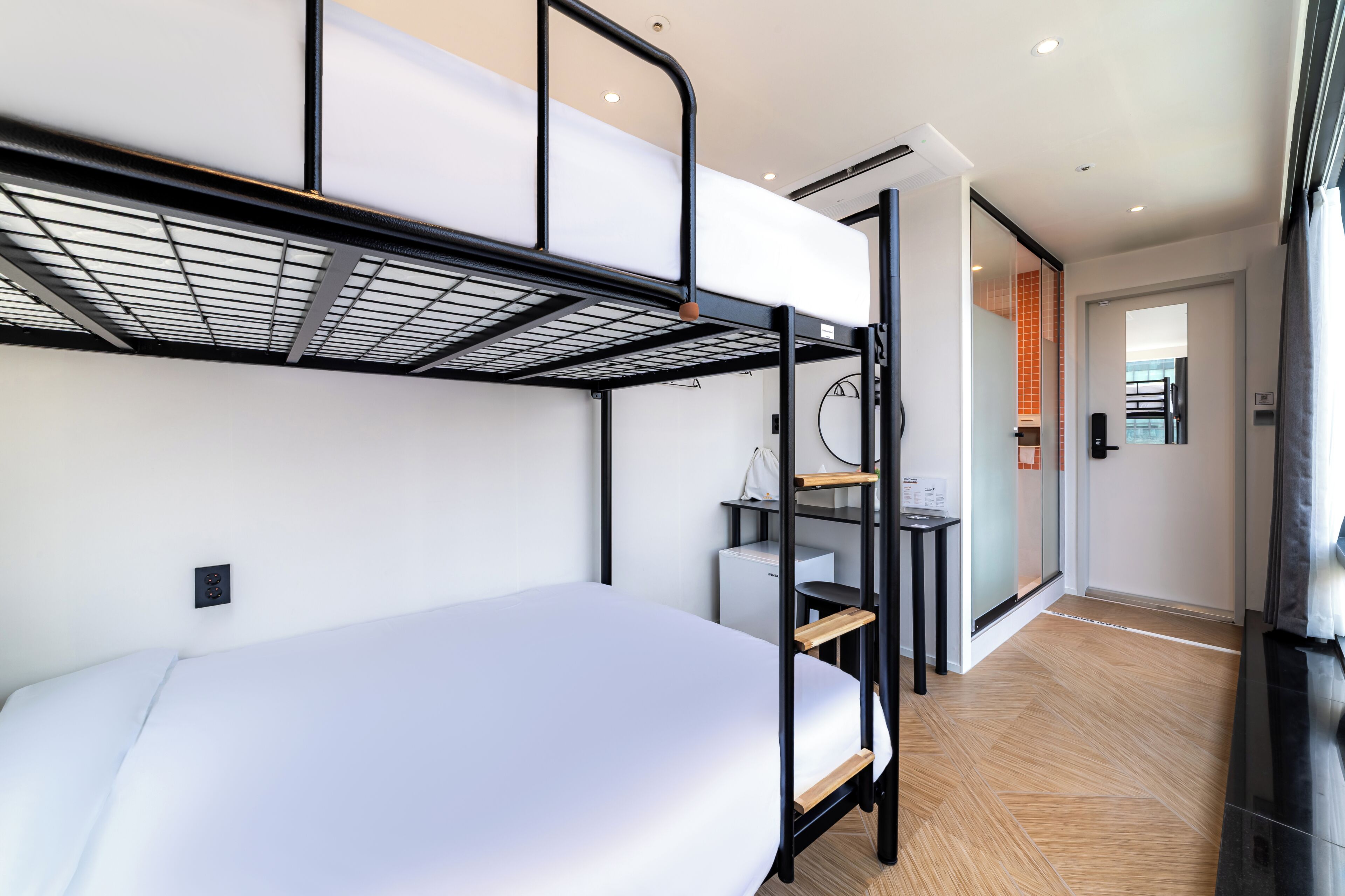 Habitación con literas, un escritorio y una puerta corredera que da a un baño.