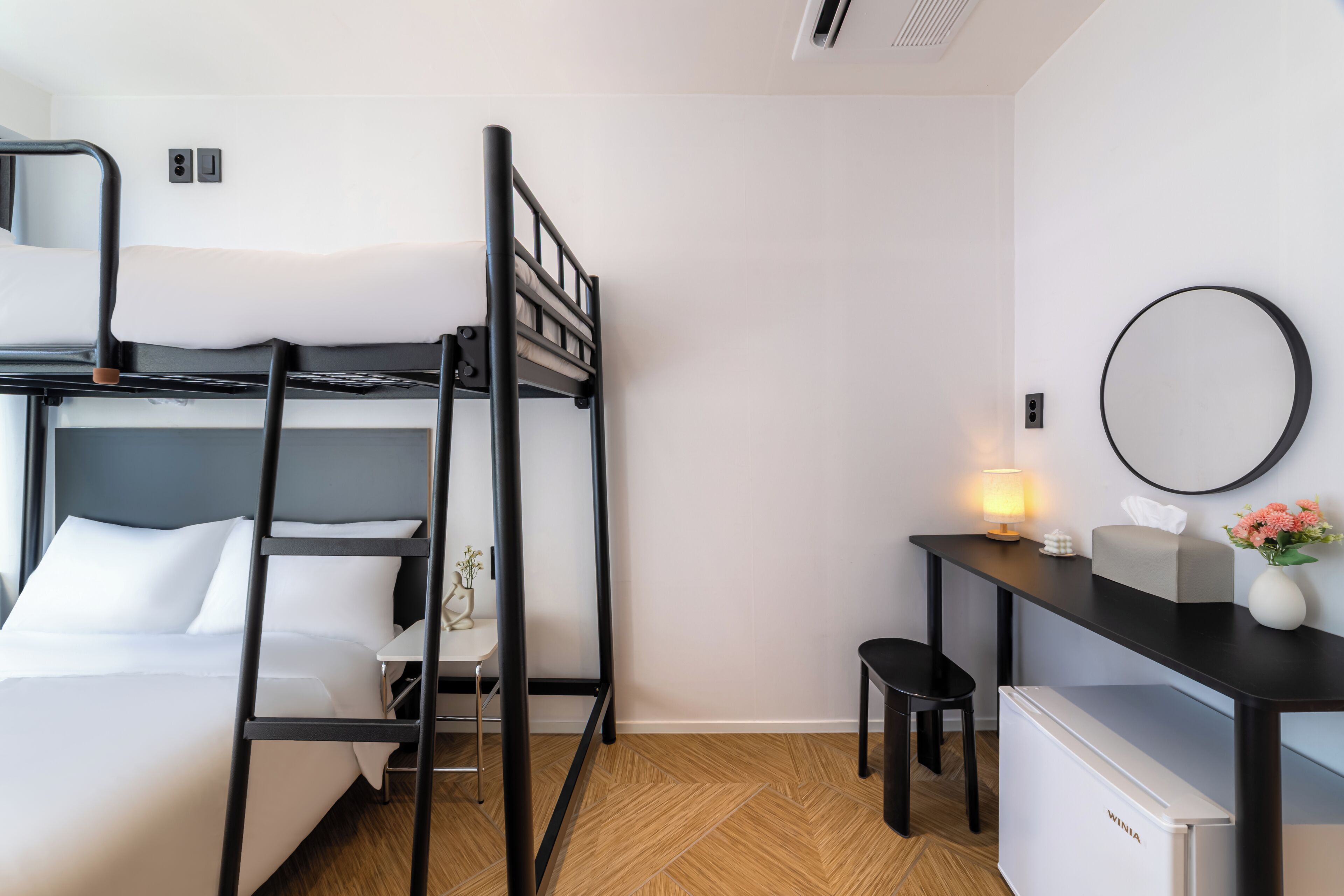A bunk bed with a desk and a small refrigerator in a hotel room.