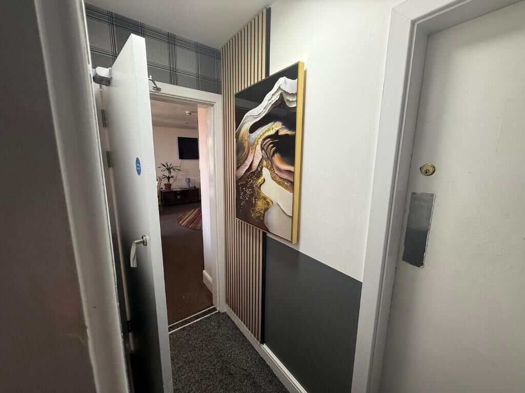 A hallway with a door, a radiator, and a wall-mounted artwork.
