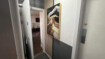 A hallway with a door, a radiator, and a wall-mounted artwork.