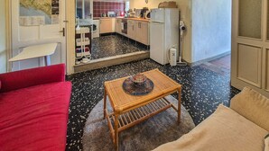 A compact living space with a kitchenette, a dining area with a table, and a red sofa. - The Tinello - Virgoletta (Virgoletta)