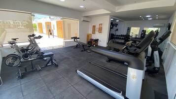A gym with cardio machines, weight benches, and dumbbells.