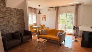 Uma sala de estar com sofá, cadeiras, mesa de centro e um espaço de jantar com mesa e cadeiras.