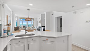 Een moderne keuken met witte kasten, een groot eiland en uitzicht naar buiten.