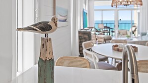 Een eetruimte met een tafel, stoelen en een decoratief beeld van een vogel.