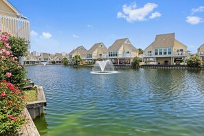 Een pand aan het water met een fontein, een rij huizen en een heldere lucht.