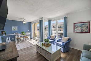 Een moderne woonkamer met een eethoek, grote ramen en een balkon.