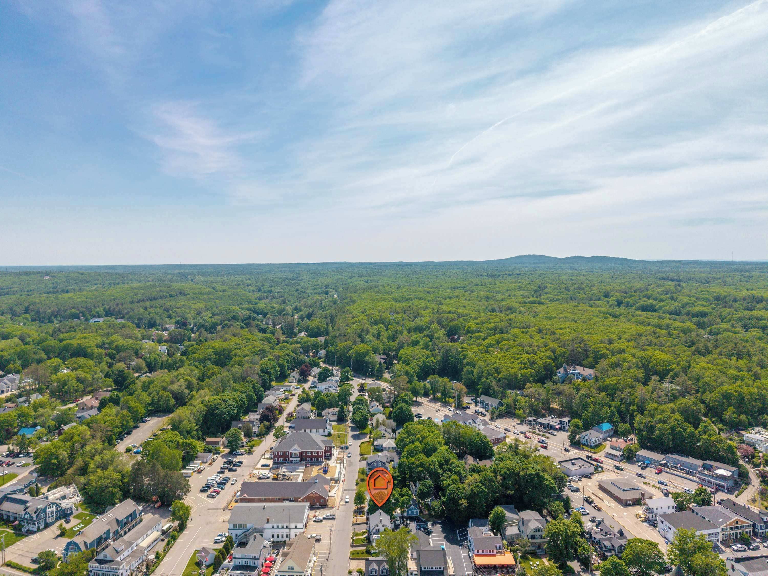 Vue aérienne d’une ville avec des bâtiments résidentiels et commerciaux, des routes et des espaces verts environnants.