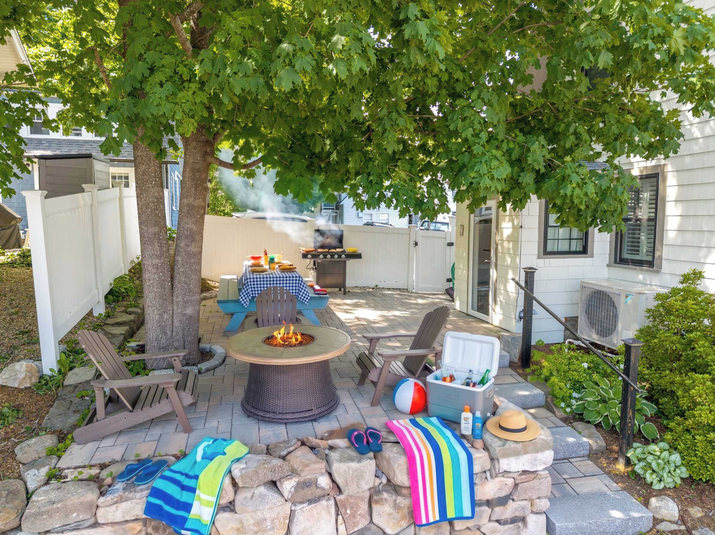 An outdoor patio with a fire pit, seating, and a grill.