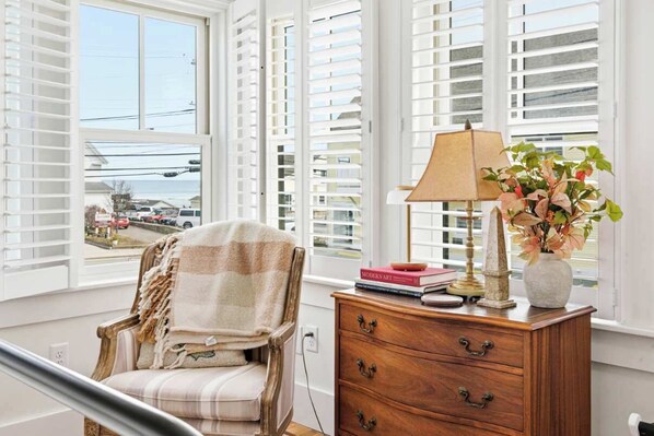 A room with a chair, a wooden dresser, a lamp, and a vase with flowers. - Casa sul Mare Near the Coast (Ogunquit)