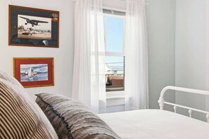 A bedroom with a bed, a window with curtains, and two framed pictures on the wall. - Casa sul Mare Near the Coast (Ogunquit)