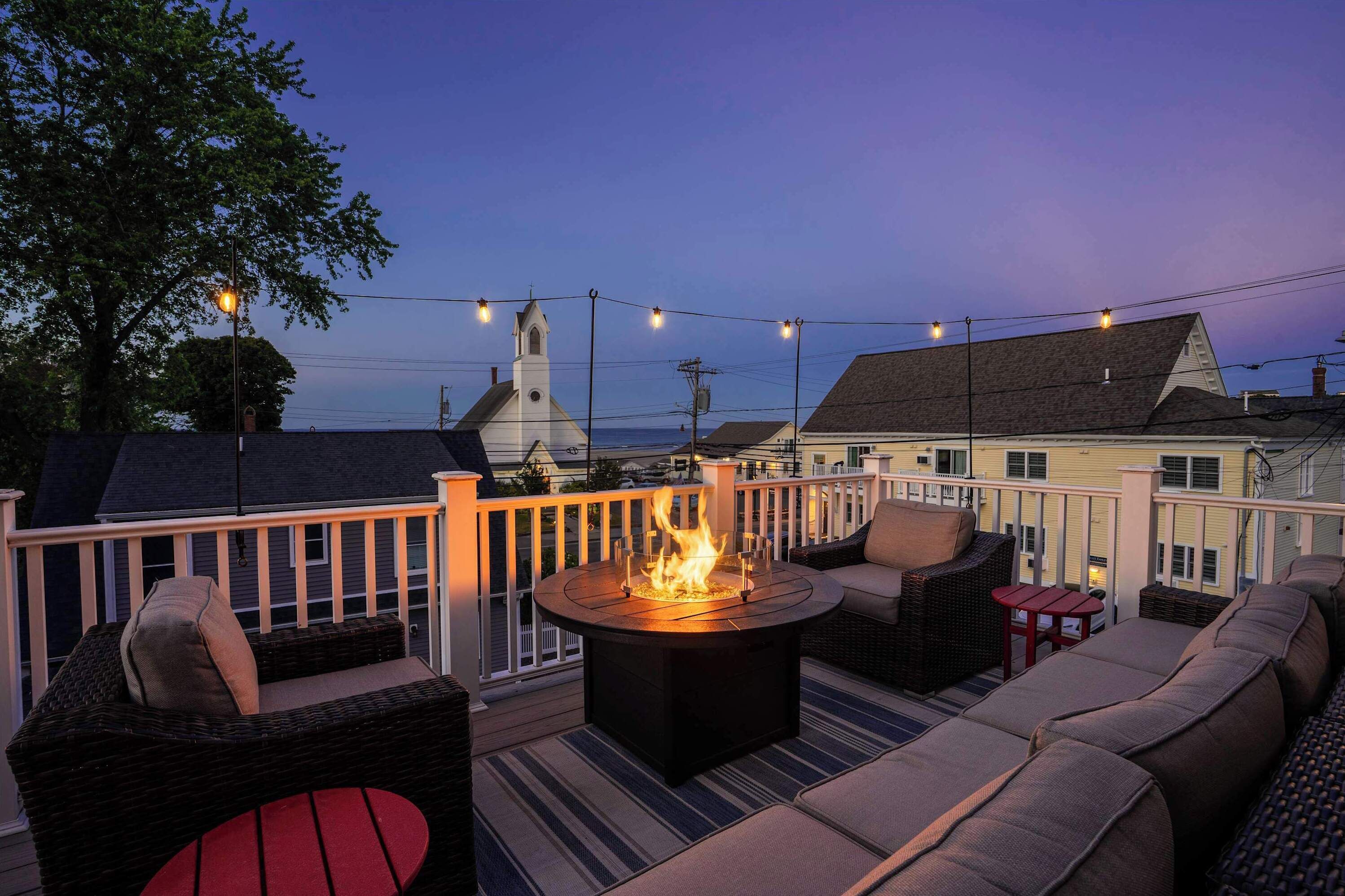 Una terraza con chimenea, mobiliario exterior e iluminación colgante.