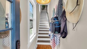 A staircase leading to a room with a view, a hanging light fixture, and a wall with hanging items. - Walk to Beach | Parking | Sleeps 10 (Asbury Park)