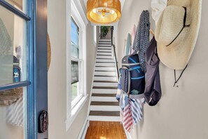 Eine Treppe führt zu einem Zimmer mit Blick, einer hängenden Leuchte und einer Wand mit dekorativen Gegenständen.