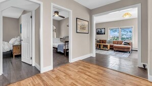 A spacious living area with a wooden floor, a sofa set, and a large window offering a view. - Walk to Beach | Parking | Sleeps 10 (Asbury Park)