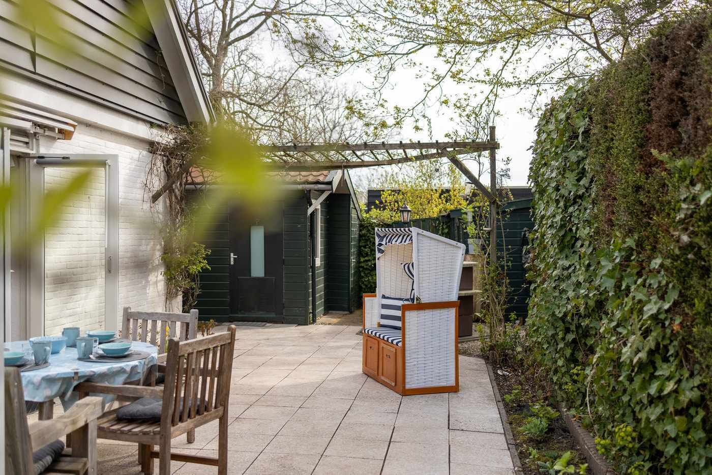 A patio area with a table set for dining, a wooden bench, and a covered seating area.