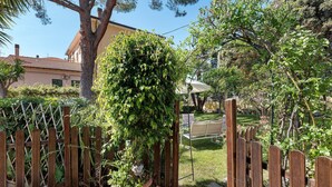 A garden with a wooden fence, a potted plant, and a house in the background.