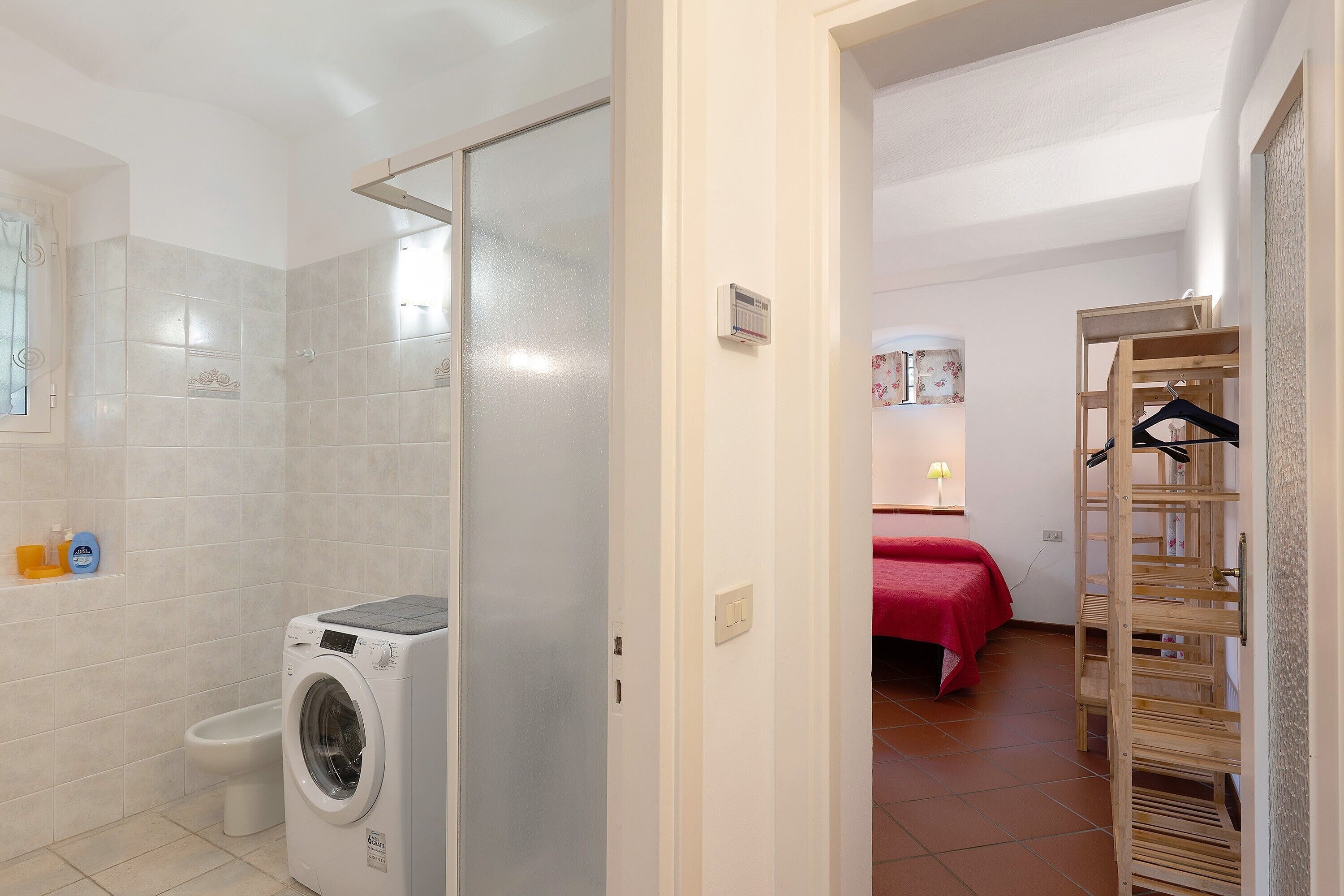 A bathroom with a washing machine, toilet, and a shower.