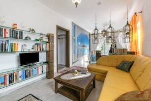 Ein Wohnzimmer mit einer Couch, einem Couchtisch, einem Fernseher und Bücherregalen.