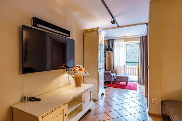 Ein Hotelzimmer mit Fernseher, Lampe, Schrank, Sofa und Fenster mit Blick.