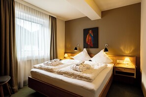 A hotel room with a large bed, two bedside tables with lamps, a painting on the wall, and a window with curtains. - Garden suite vacation apartment with pool in Saalbach-Hinterglemm (Hinterglemm)