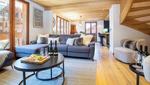 Een moderne woonkamer met een bank, een salontafel met eten en drinken, en een keuken op de achtergrond.